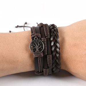 Close-up of multilayer leather bracelet set featuring a bronze tree of life charm detail