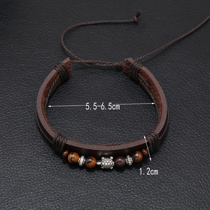Dettaglio del bracciale in pelle intrecciata con occhio di tigre e ciondolo tartaruga