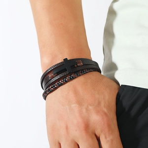 Close-up of men's multilayer leather bracelet with a matte black cross and braided cords
