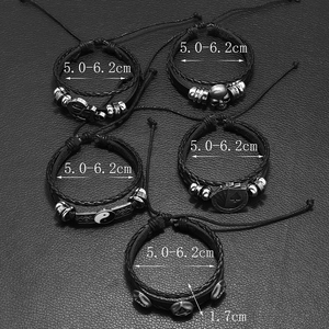 Close-up of adjustable skull and ying-yang charms on a 5-piece black braided leather bracelet set