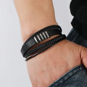 Gros plan d'un bracelet multicouche en cuir noir tressé avec cinq curseurs métalliques argentés