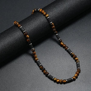 Dettaglio della collana di perle occhio di tigre e lava su un supporto cilindrico nero