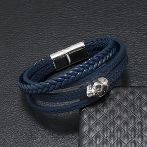 Macro detail of navy braided leather bracelet with silver skull charm and magnetic clasp