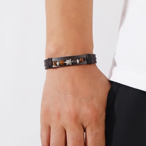 Dettaglio del bracciale in pelle multistrato con perline occhio di tigre e ciondolo a tartaruga