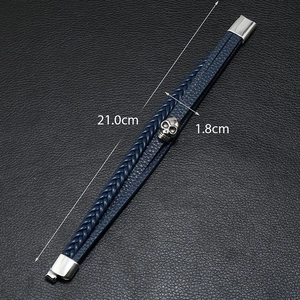 Macro view of men's leather braided bracelet with silver skull charm and 21cm length scale