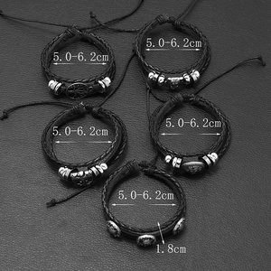 Detail of 5-piece retro braided leather bracelet set with metallic skull and tree charms