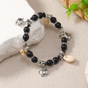 Close-up of black beaded bracelet featuring vintage silver turtle and shell pendants on stone