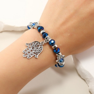 Vista de detalle de los dijes de mano de Fátima y cuentas de cristal azul en la pulsera