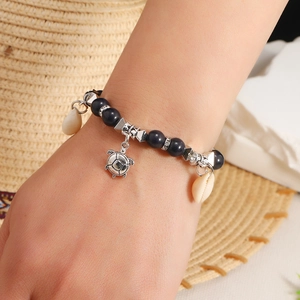 Detail of bohemian ocean style beaded bracelet with blue beads and sea turtle charm