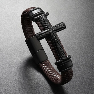 Macro shot of brown braided leather bracelet with embossed black cross and magnetic clasp