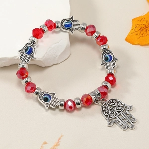 Detalle de la pulsera de cuentas rojas facetadas con mano de Fátima y dijes de ojo turco
