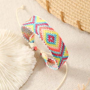 Macro detail of Bohemian hand-woven bracelet with vibrant geometric diamond embroidery