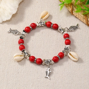 Detailed macro shot of bohemian red beaded bracelet with fishbone and seashell charms