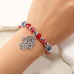 Detalle de la pulsera de cuentas rojas con mano de Fátima y dijes de ojo turco