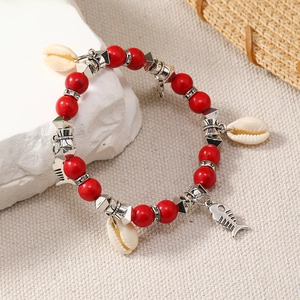 Detail of bohemian ocean bracelet with red beads, shell charms, and silver fish pendant