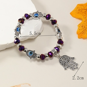 Detalle de pulsera de cuentas púrpuras con mano de Fátima, ojo turco y colgante de metal