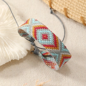 Macro detail of Bohemian woven bracelet with geometric patterns and adjustable gray cord