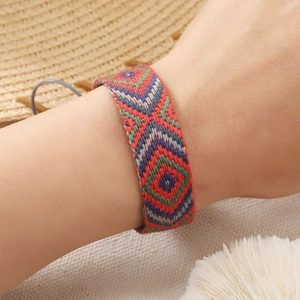 Detail of bohemian hand-woven bracelet with geometric patterns on a beach background