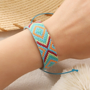 Macro shot of colorful Bohemian woven bracelet with geometric patterns and adjustable blue cord