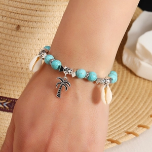 Detail of turquoise beaded bracelet with silver palm tree and white seashell charms
