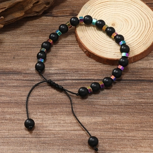 Détail de perles noires mates avec cubes métalliques irisés sur cordon tissé réglable