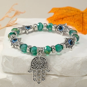 Detalle de pulsera de cuentas de cristal verde con mano de Fátima y dijes de Ojo Turco