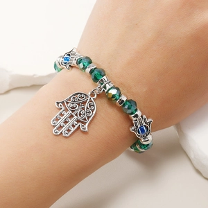 Macro detallada de la pulsera de cuentas verdes con mano de fátima y amuletos de ojo turco