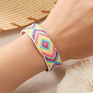 Close-up of a handmade bohemian rainbow woven bracelet on wrist with summer beach vibe