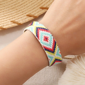 Close-up of Bohemian handmade woven bracelet with vibrant geometric diamond patterns on wrist