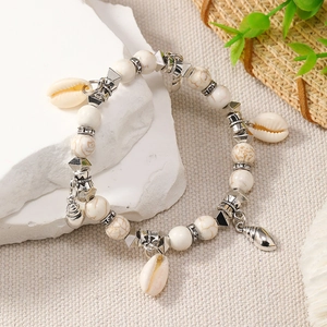 Detail of bohemian shell bracelet with marble beads and silver charms on white stone