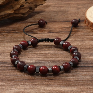 Détail du bracelet en perles de bois rouge foncé avec des entretoises sur fond de bois