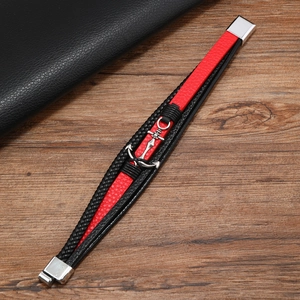 Détail du bracelet en cuir multicouche rouge et noir avec ancre argentée et fermoir magnétique
