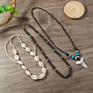 Detail of bohemian ocean necklaces featuring shells, wood beads, and shark tooth pendants