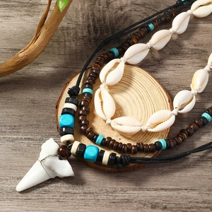 Detail of multi-layer ocean necklace with shell beads and large white shark tooth pendant