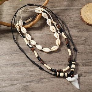 Detailed close-up of bohemian layered necklace with shell beads and white shark tooth pendant