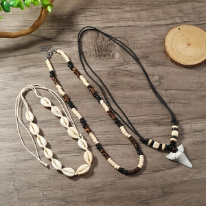 Detail view of ocean-style multilayer necklaces with cowrie shells and shark tooth pendant