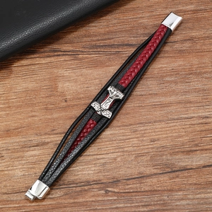 Detail of multi-layer braided leather bracelet featuring a silver Mjolnir pendant on wood