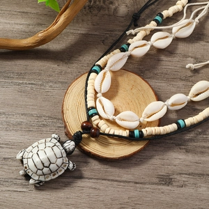 Detail of bohemian necklace with turtle pendant, white shells and wood beads on wood