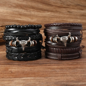 Detail view of multi-layered leather bracelets with metallic bull skull charm on wood