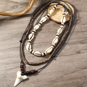 Macro detail of natural white seashells and wood beads with shark tooth pendant