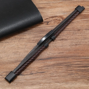 Detail of multi-layer braided leather men's bracelet with a black metal clasp on wood