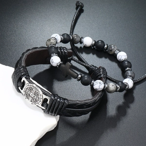 Detail van retro herenarmbanden met kruisbedeltje en gevlochten leer