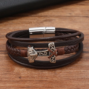 Detailed close-up of brown braided leather bracelet with silver Viking Thor's Hammer charm