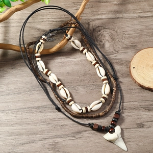 Detail of bohemian layered necklace with white shells, brown wood beads and shark tooth pendant
