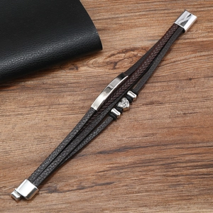 Macro detail of multi-layered brown leather bracelet with silver heart bead and magnetic clasp