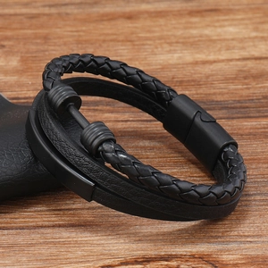 Close-up of men's layered black leather bracelet with braided strands and magnetic clasp