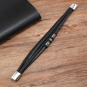 Macro view of men's leather braided bracelet with dragon pattern beads and magnetic clasp