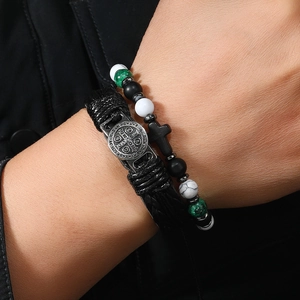 Detail van de gelaagde lederen gevlochten band en kralenarmband met zilveren kruisje