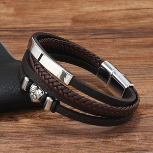 Detail of multi-layer brown braided leather bracelet featuring a silver skull and magnet clasp