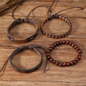 Detail eines vierteiligen Sets aus handgefertigten Lederarmbändern und Holzperlen auf Holzgrund